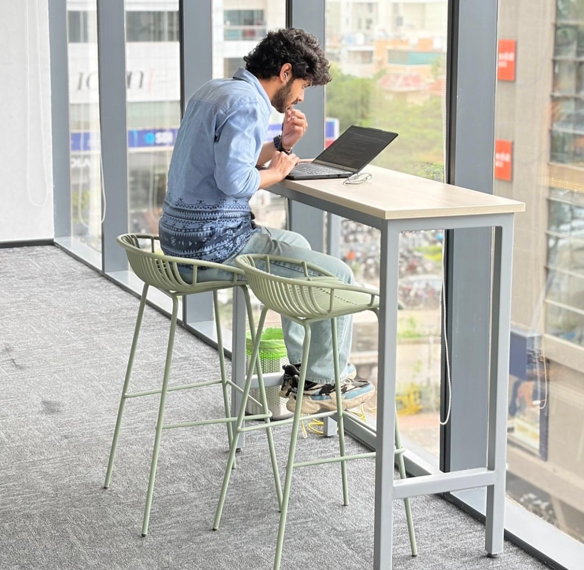 Employee working comfortably at a high desk by the large windows